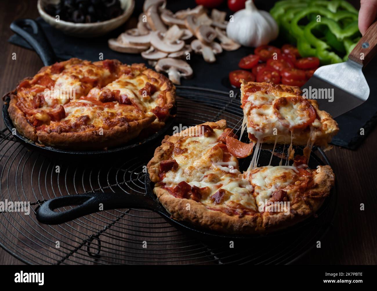 Close up of two individual deep dish pan pizzas with a slice taken out