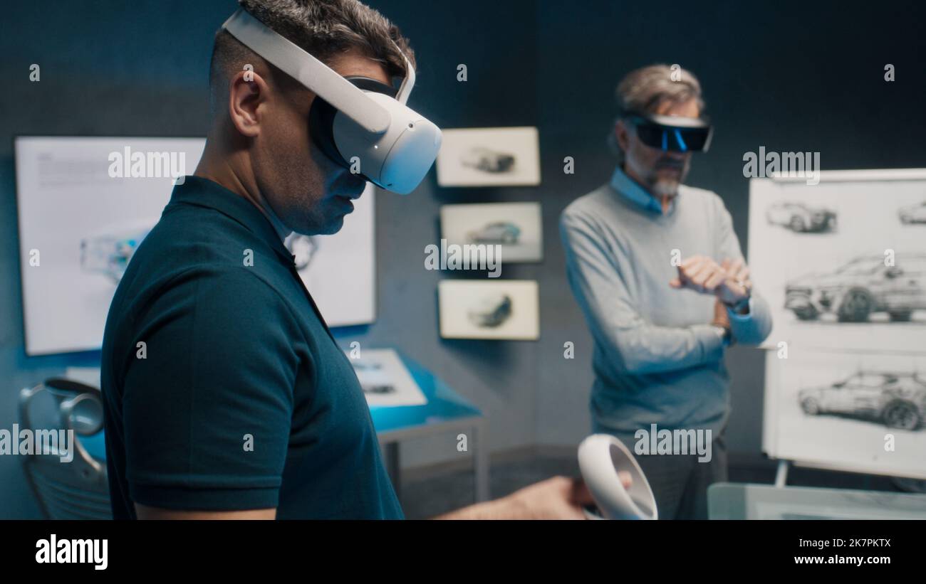 Automotive professional engineers with VR glasses talk about vehicle production while standing in a high tech office. Car design analysis and improvement. Stock Photo