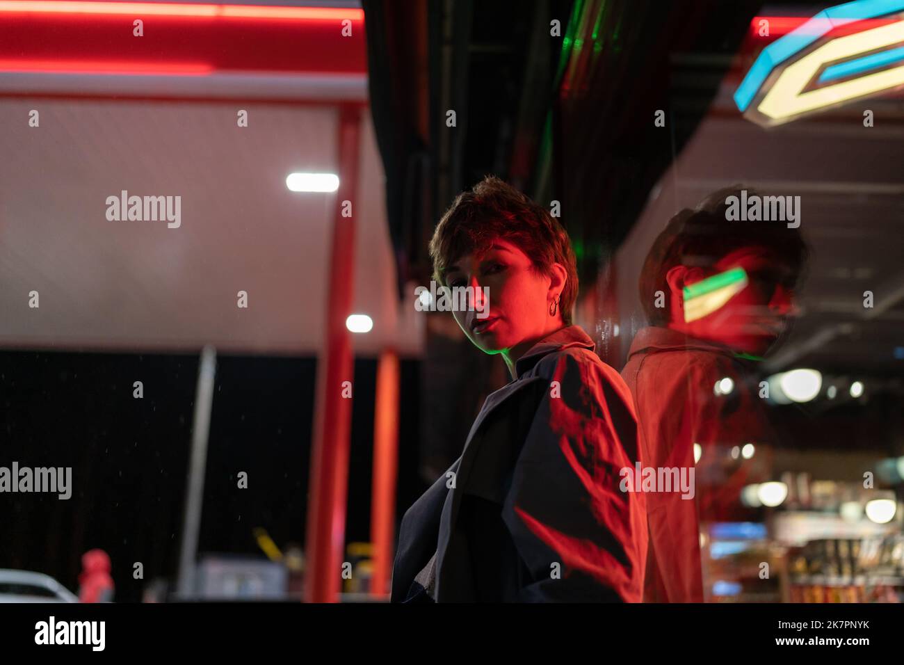 European woman is standing near with market windshield in which lighting fixtures are reflected Stock Photo