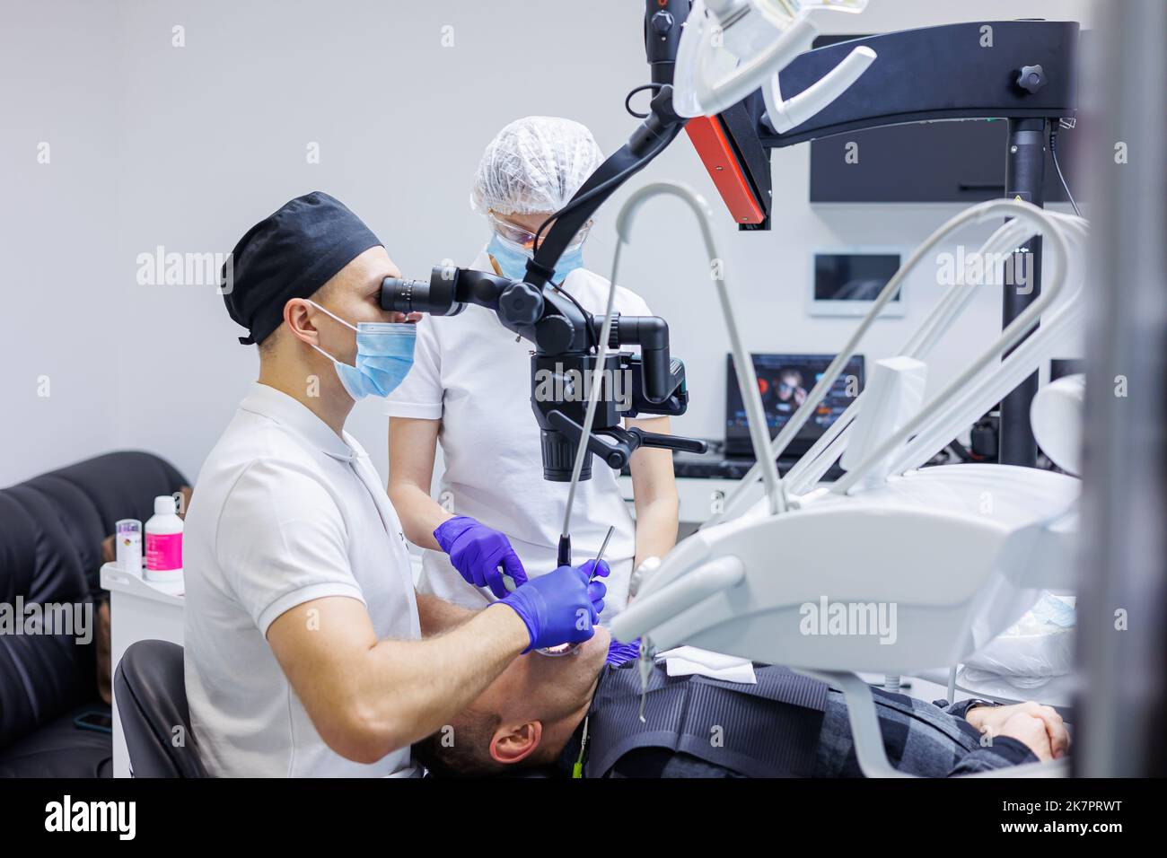 Dentist and assistant check patient's teeth with dental tools