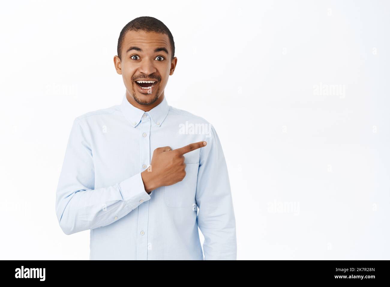 Smiling handsome man pointing right, showing direction, demonstarting promo, standing over white background Stock Photo