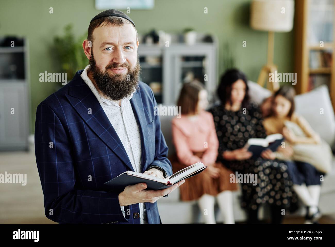 Waist up portrait of bearded jewish man wearing kippah and looking at camera holding book, copy space Stock Photo