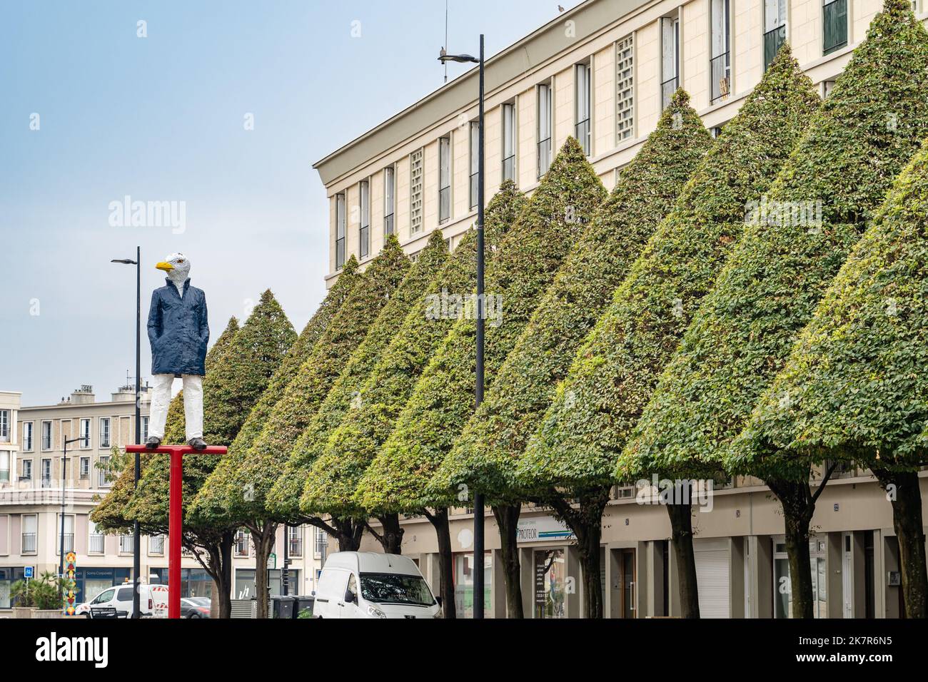 Manicured trees and a birdman statue line the square at the natural