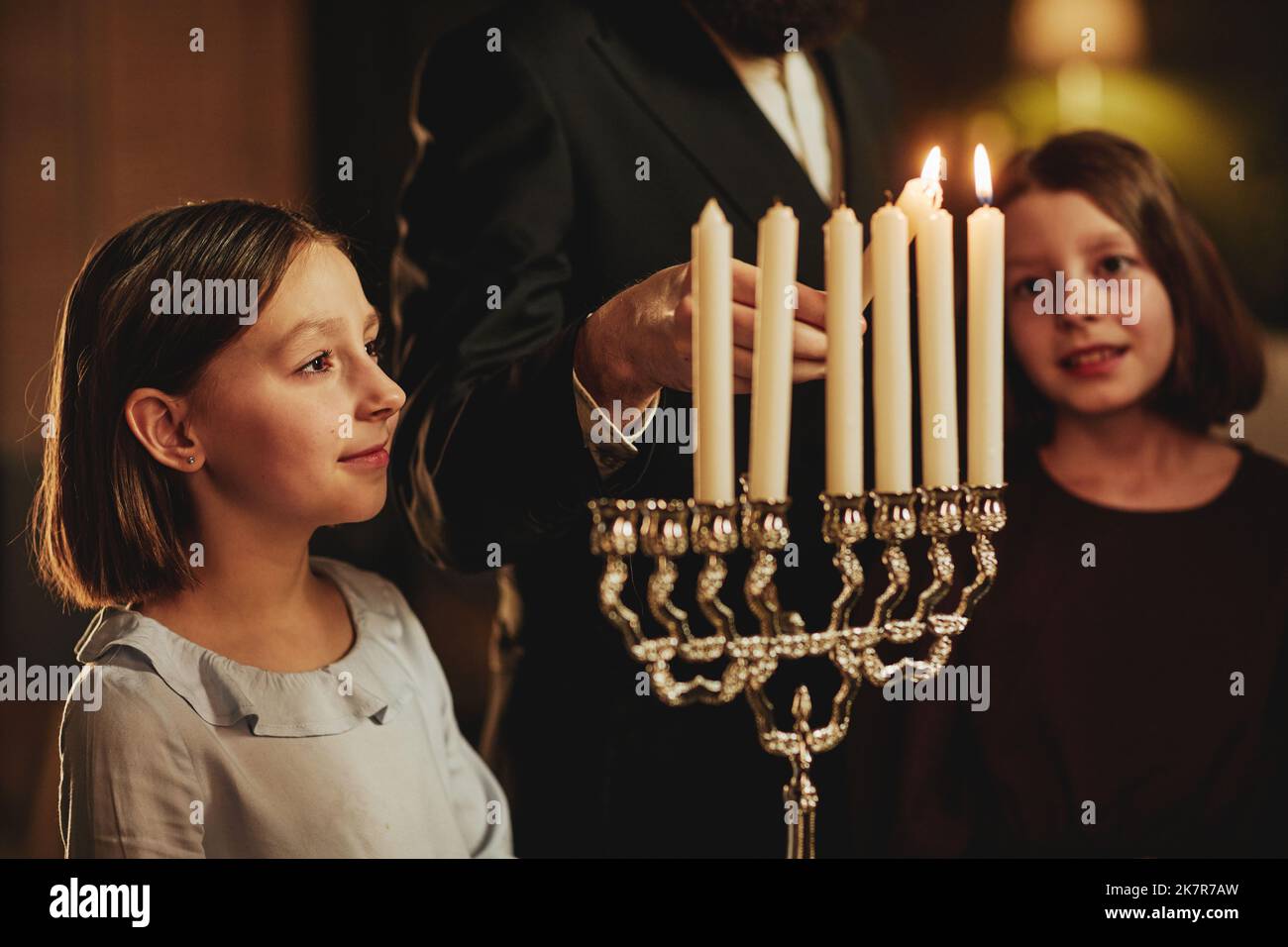 Side view portrait of young girl looking at menorah candle during