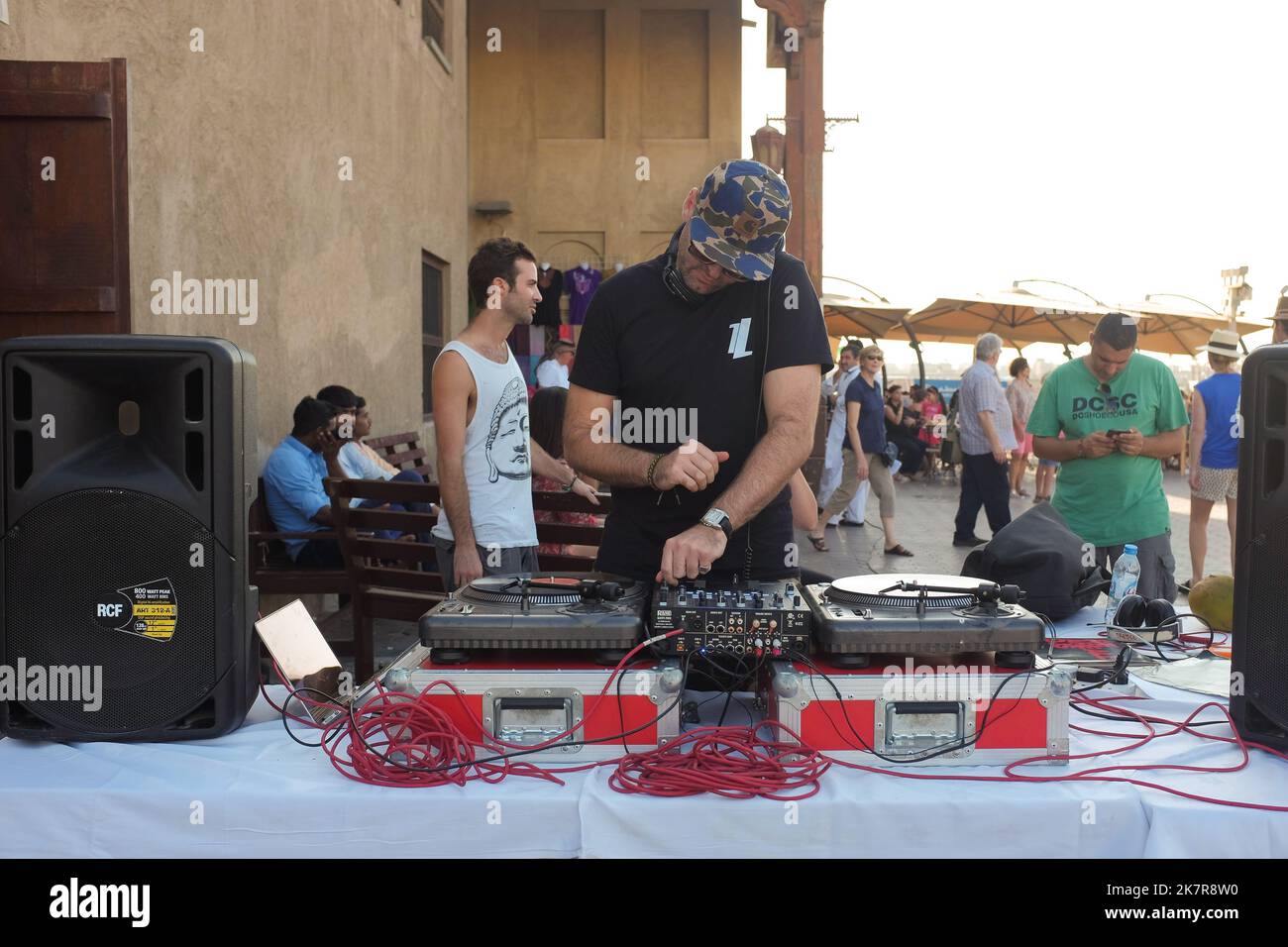 Male DJ with professional turntable, mixer, and speakers provide music and ambiance to a hip art fair in Dubai, UAE. Sunny weekend outdoor summer event. Stock Photo