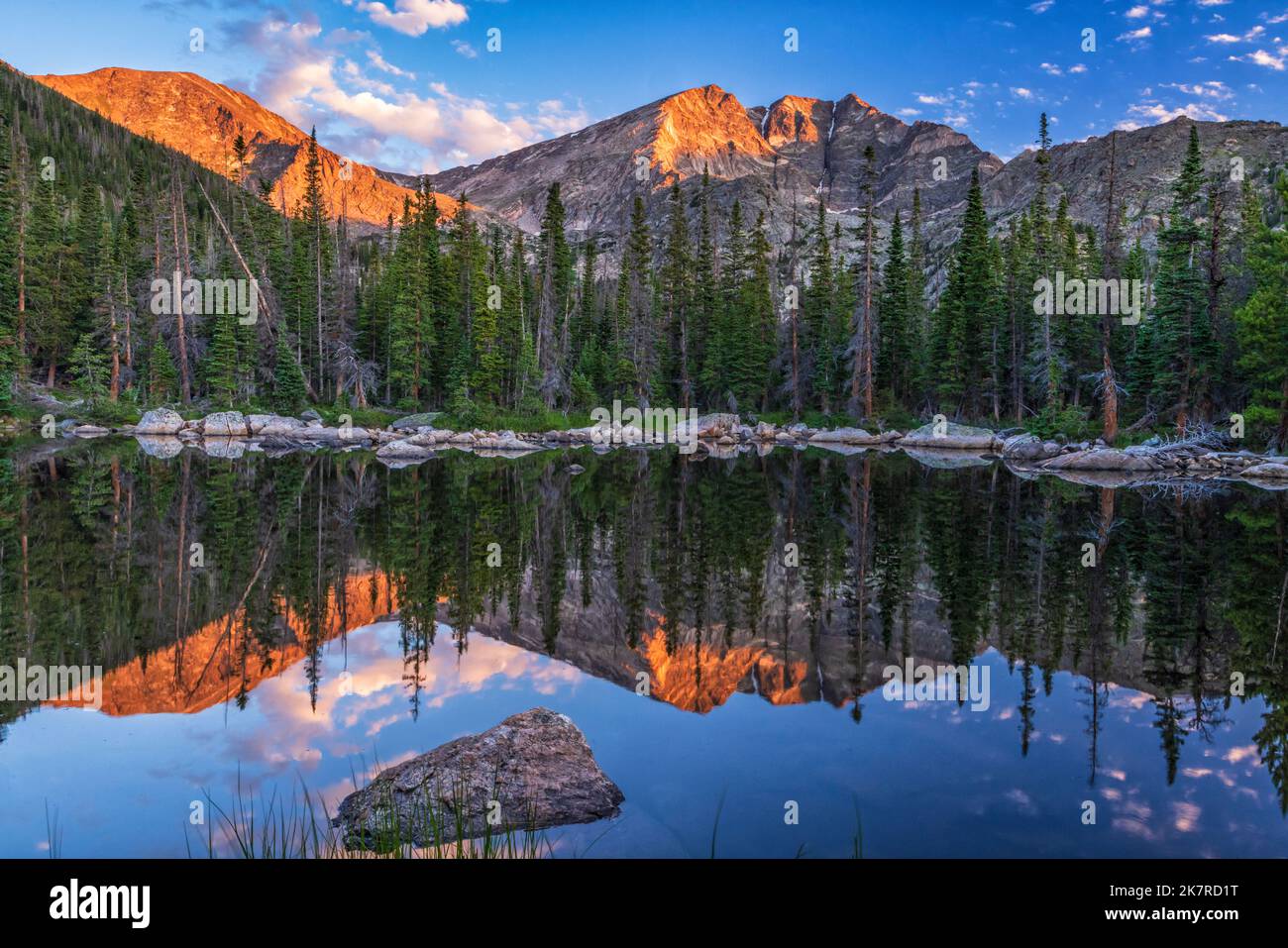 Ypsilon Mountain and Mount Chiquita are reflected in the calm water of Chipmunk Lake with the first light of golden hour in Rocky Mountain National Pa Stock Photo