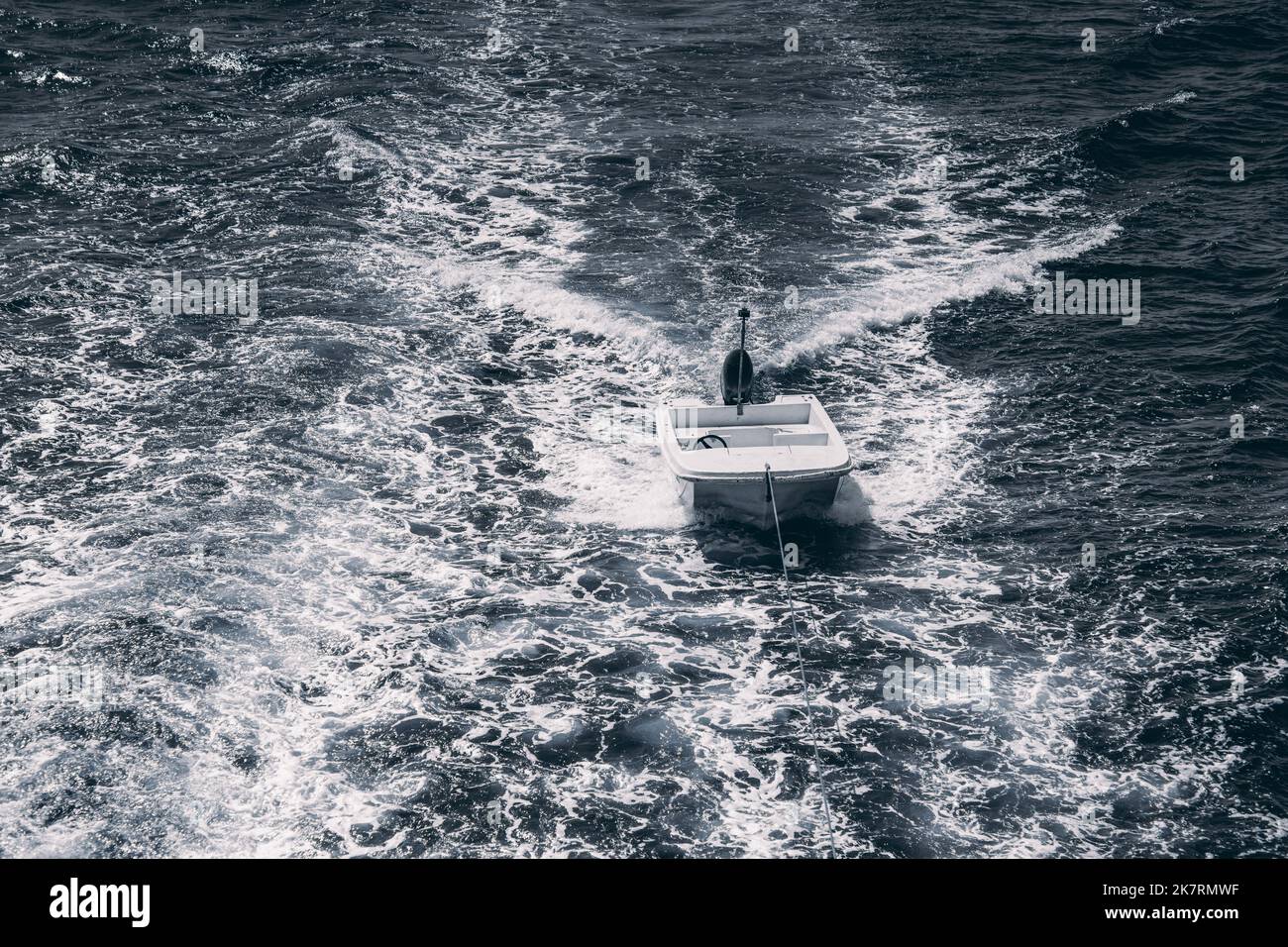 View of an empty motorboat tied behind the main yacht surrounded by ...