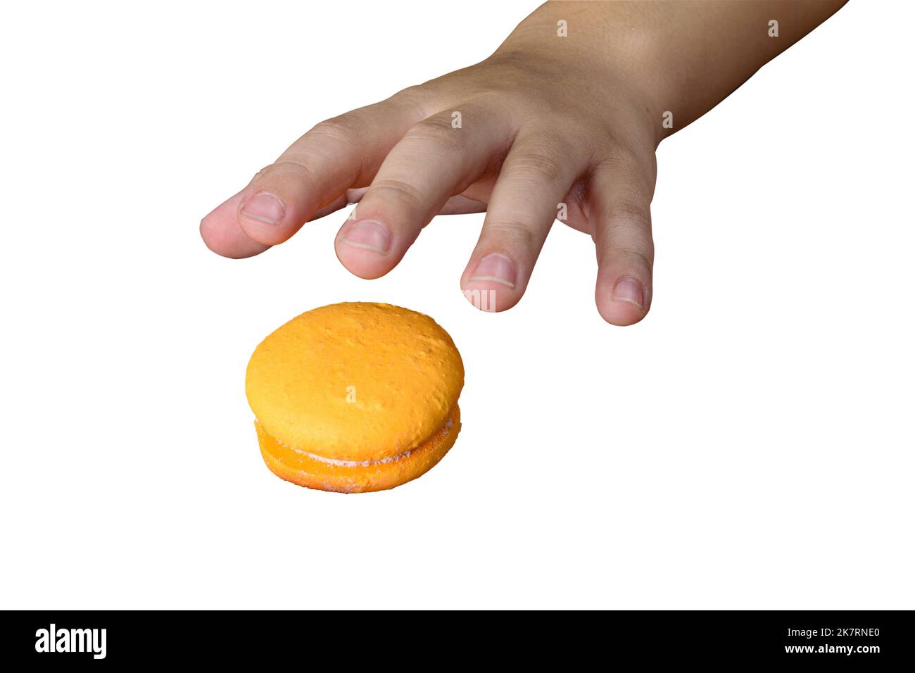 Child's hand going to pick up a yellow macaron (white background). Stock Photo