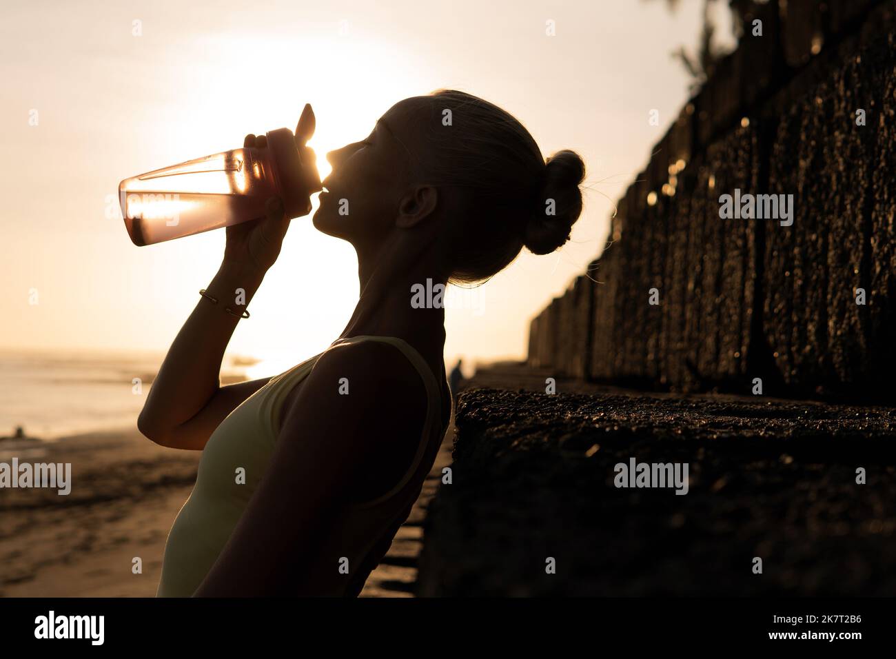 beautiful young woman drinking water. bali sunset Stock Photo Alamy
