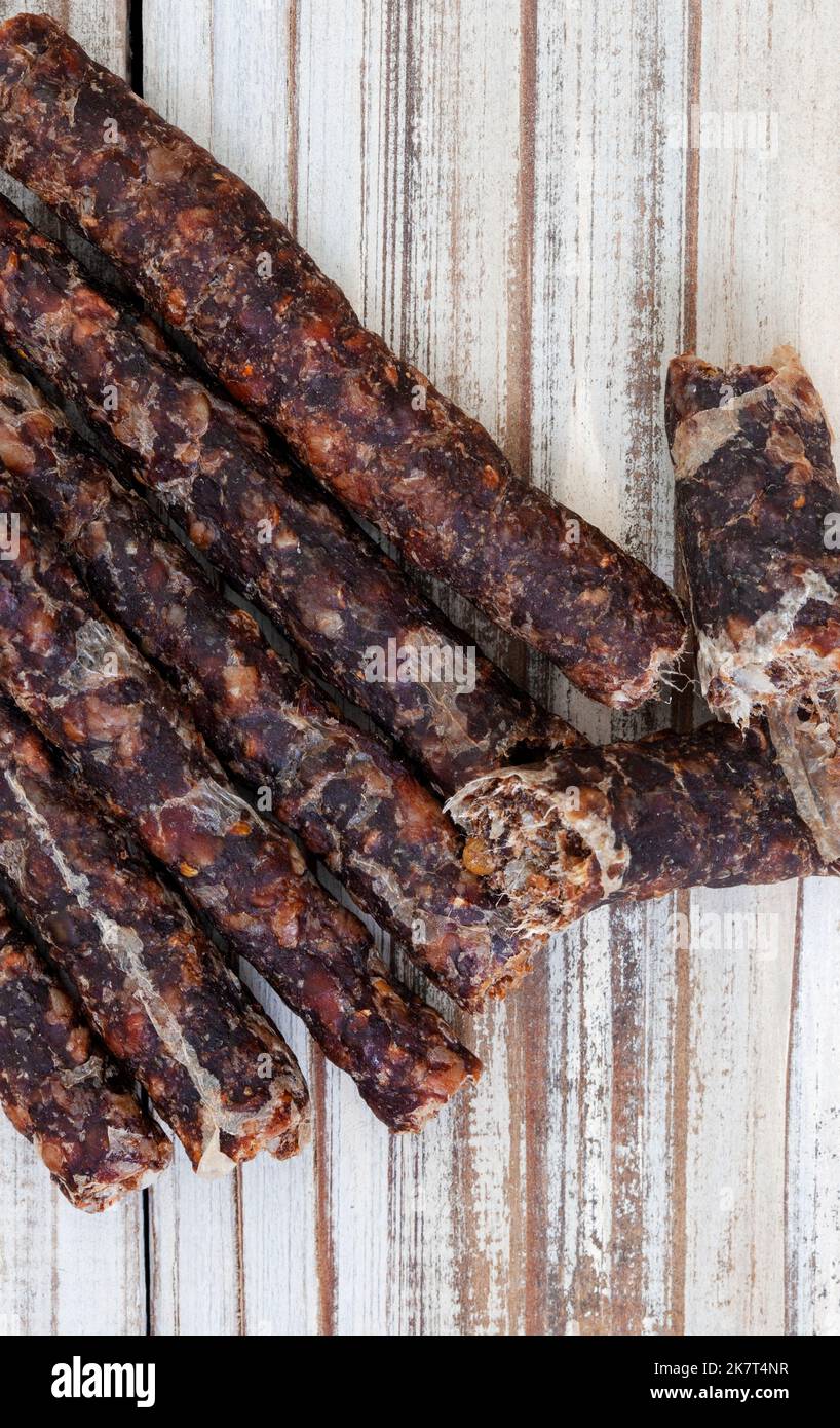 Traditional South African dry wors flat lay on rustic white wooden table with copy space. Stock Photo