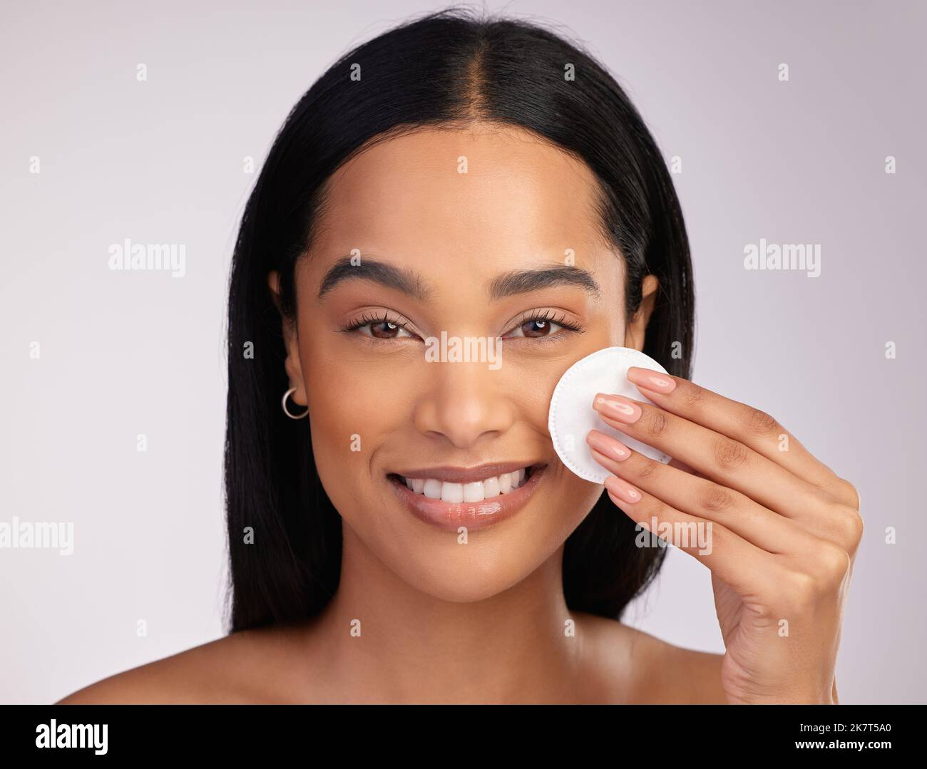 No clogged pores here. Cropped portrait of an attractive young woman exfoliating her face against a pink background. Stock Photo