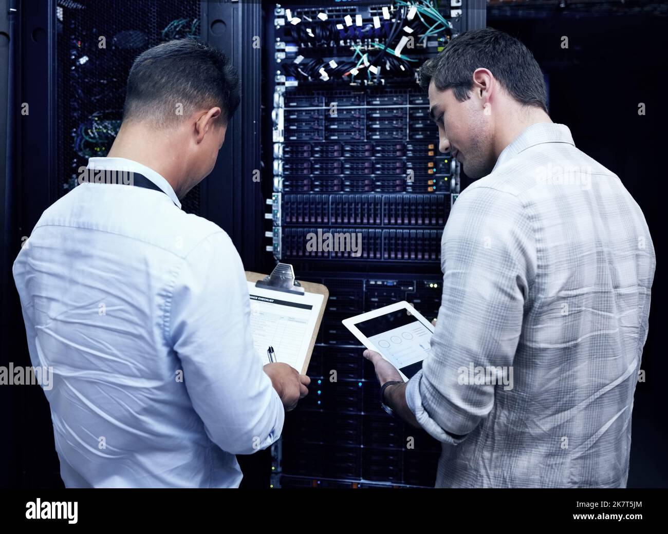 Two of the best tech gurus in town. two technicians working together in a server room Stock