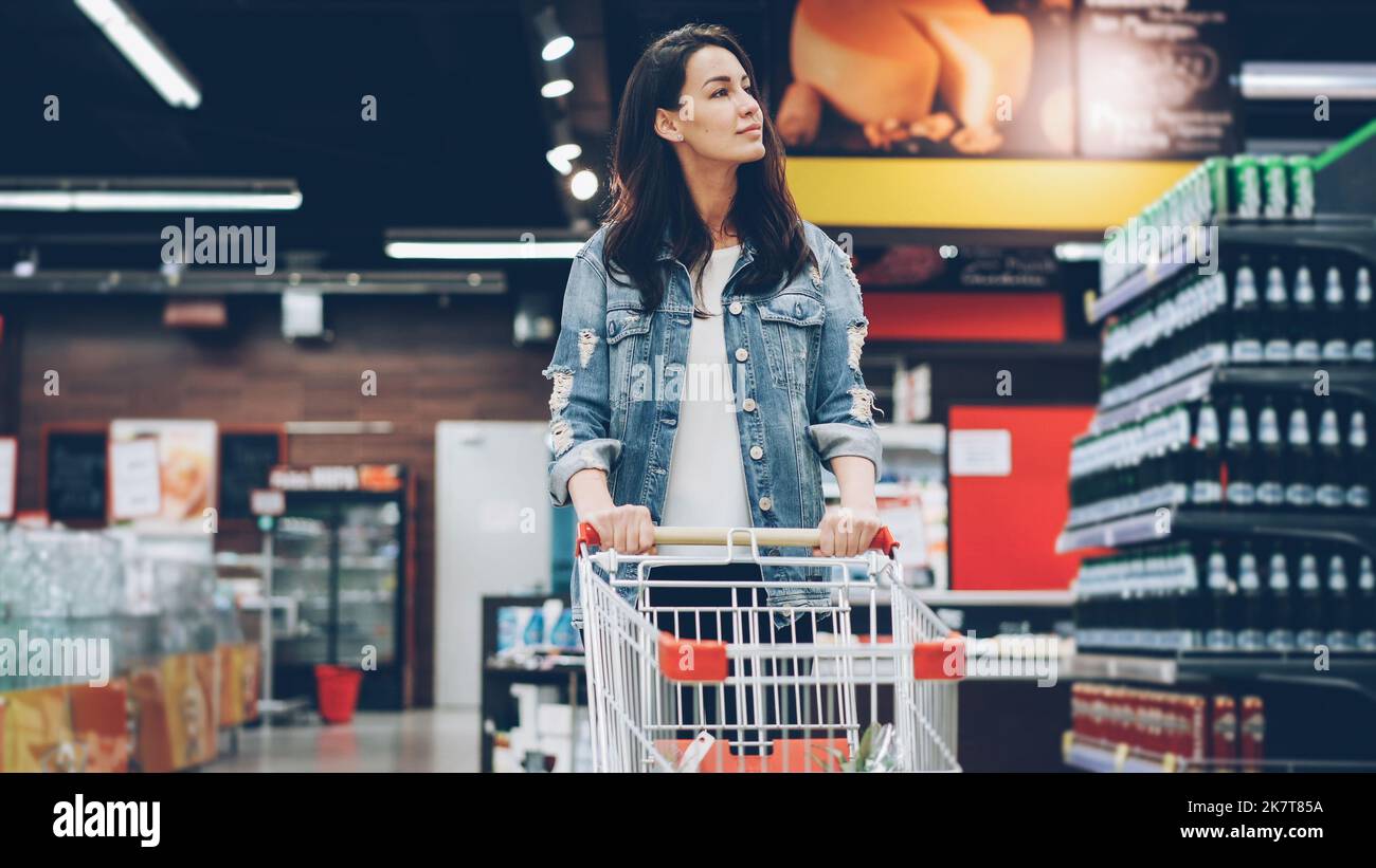 Pretty young lady in casual clothes is walking in grocery store