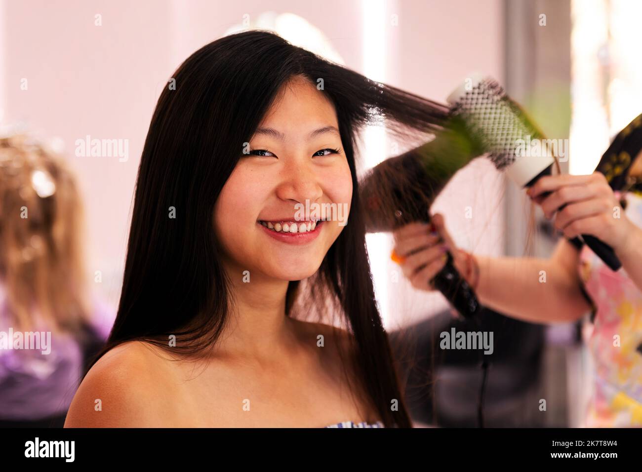 stylist combing woman's hair with brush and dryer Stock Photo - Alamy