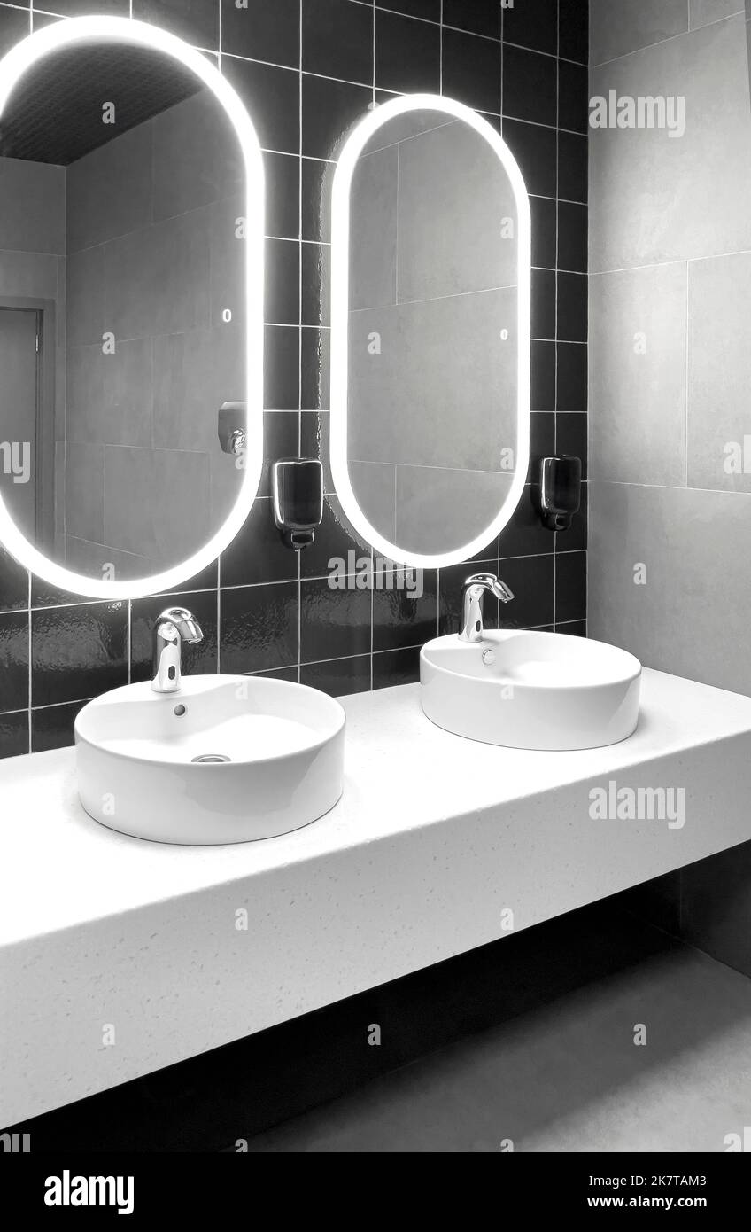 Faucets with washbasin in public restroom in grey colors Stock Photo