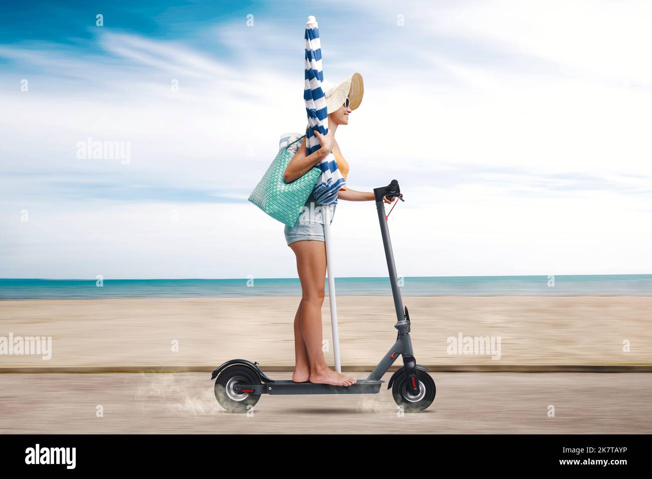 Happy woman on vacations, she is riding an electric scooter and going to the beach Stock Photo