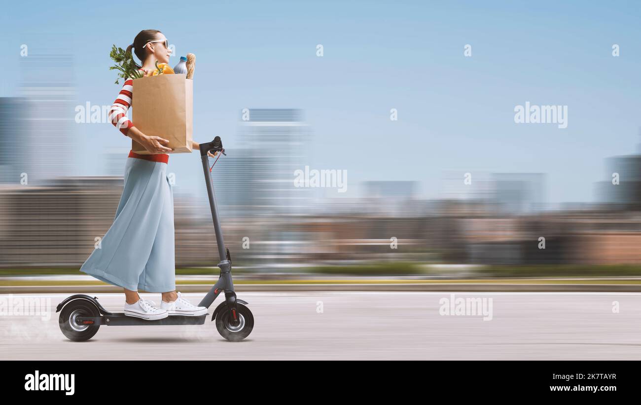 Young woman carrying a paper bag with groceries and riding a fast