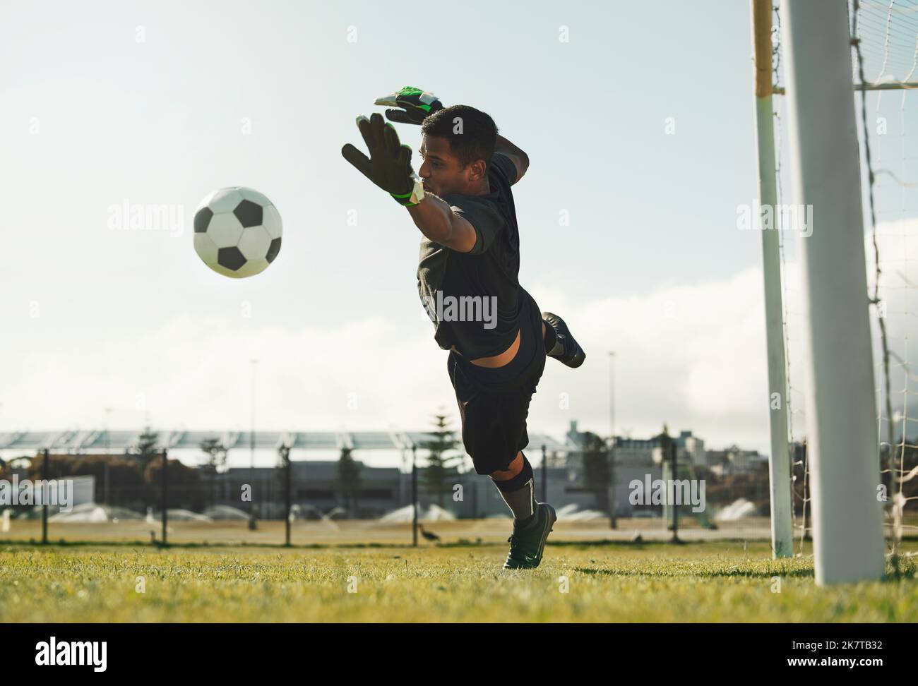 Soccer, goalkeeper and jump, saving ball from goals at outdoor sports