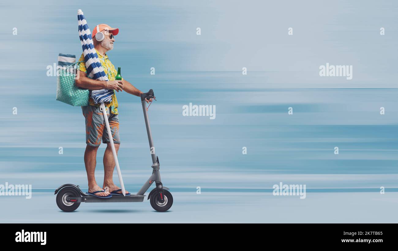 Funny happy senior tourist going to the beach, he is holding a beach umbrella and riding a fast