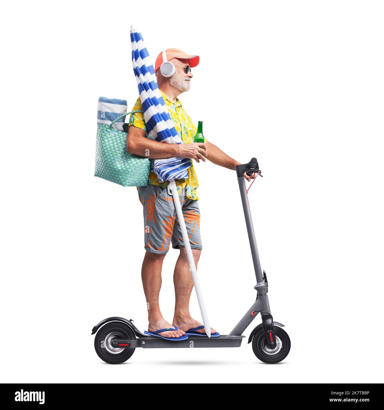 Funny senior tourist going to the beach on his electric scooter, he is holding a beach umbrella, isolated on white background Stock Photo