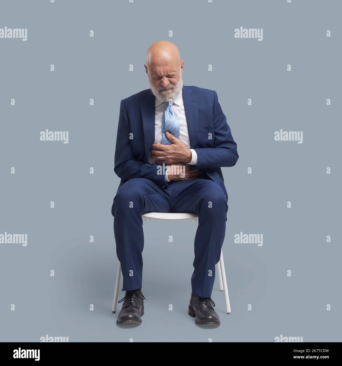 Senior man sitting on a chair and having a bad stomach ache Stock Photo