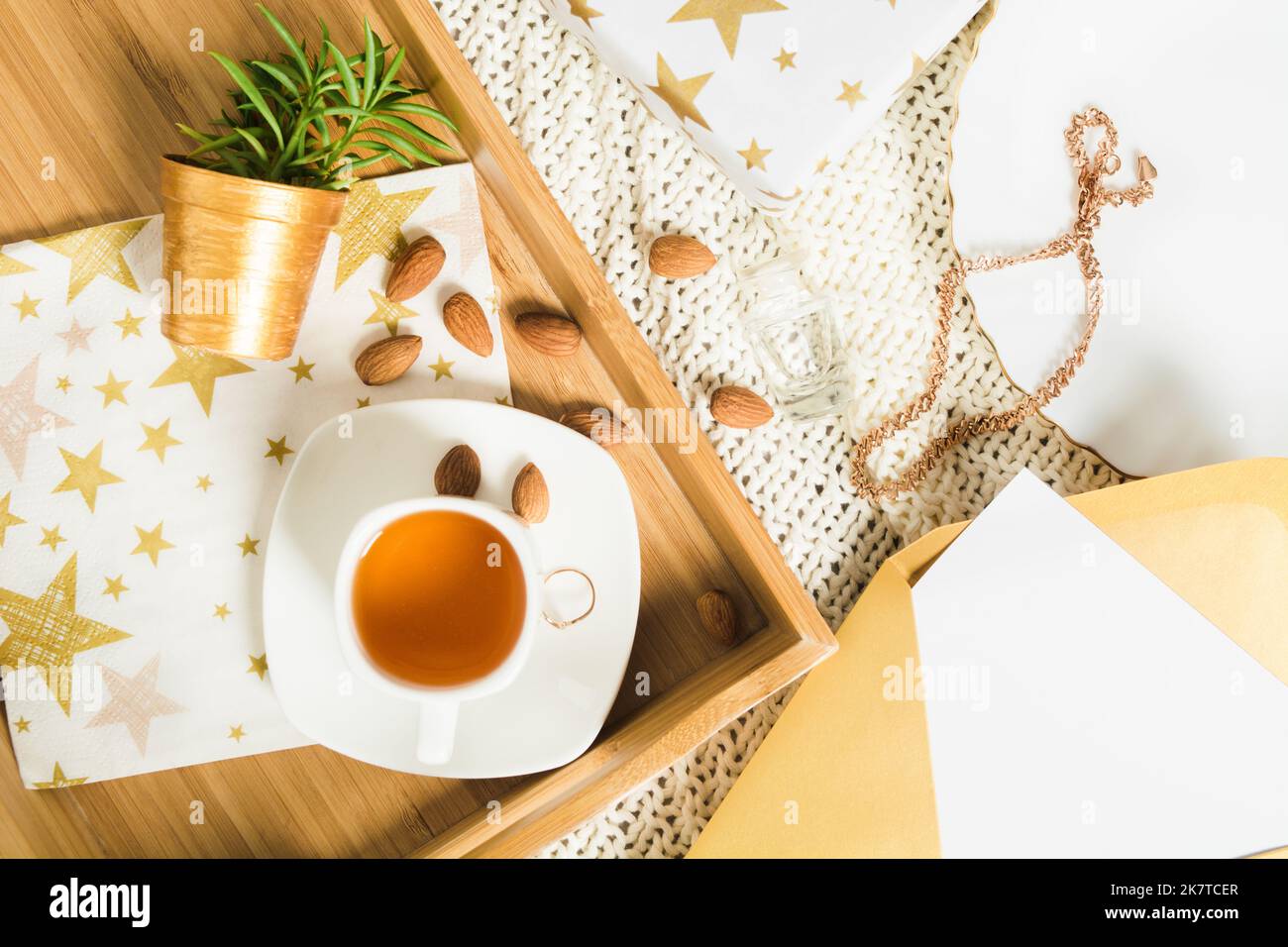 Autumn flat lay with tea on wooden tray, giftand letter in golden envelope Stock Photo