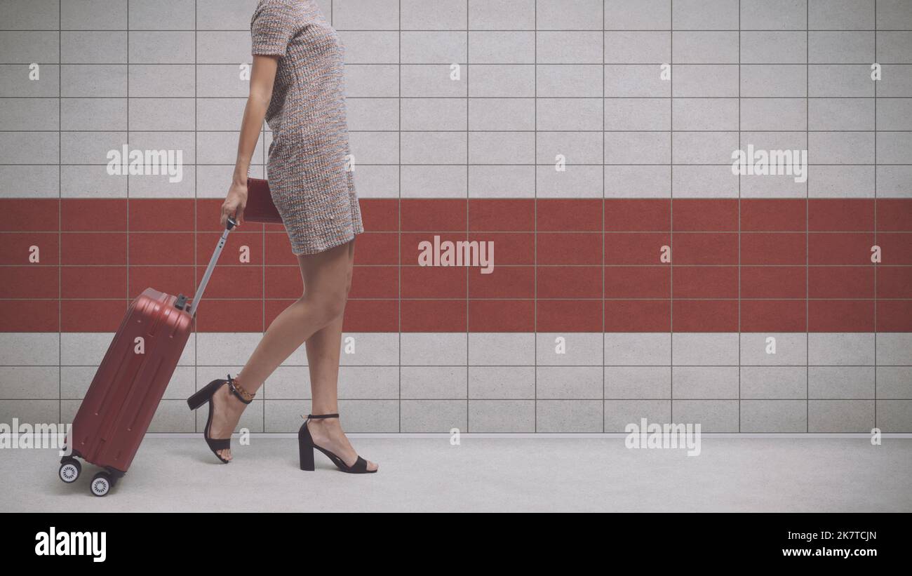 Young elegant woman traveling alone, she is pulling her trolley bag at