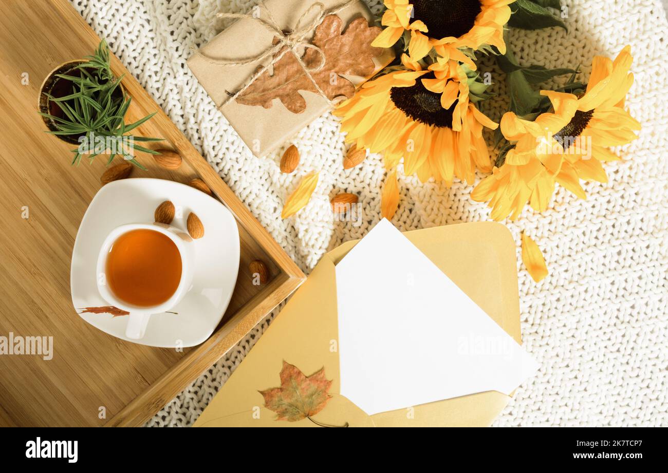 Autumn flat lay with mockup letter in golden envelope, tea, sunflowers and gift  Stock Photo