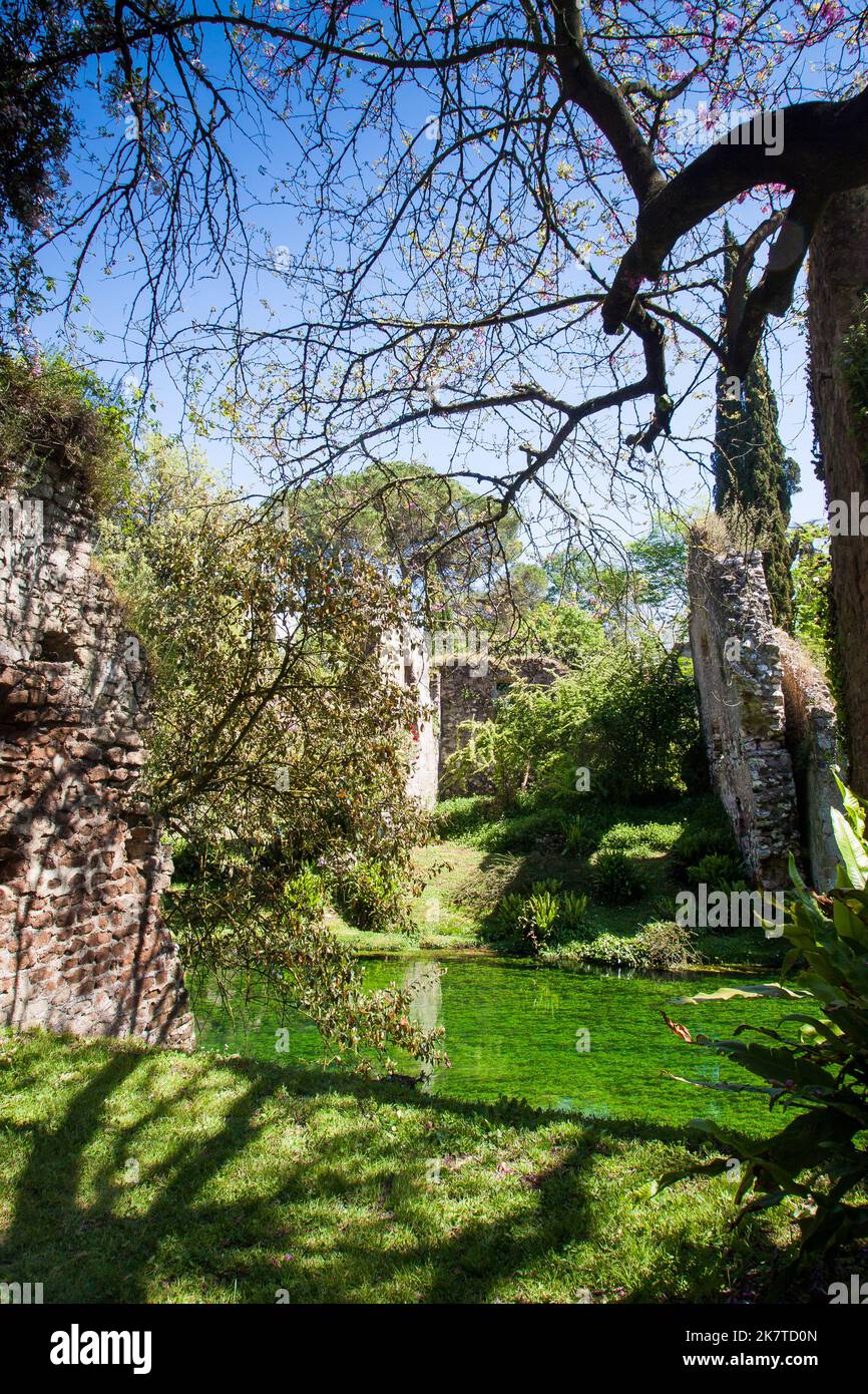 View of the river Ninfa among trees and ruins in spring in Garden of Ninfa, Lazio, Italy Stock Photo