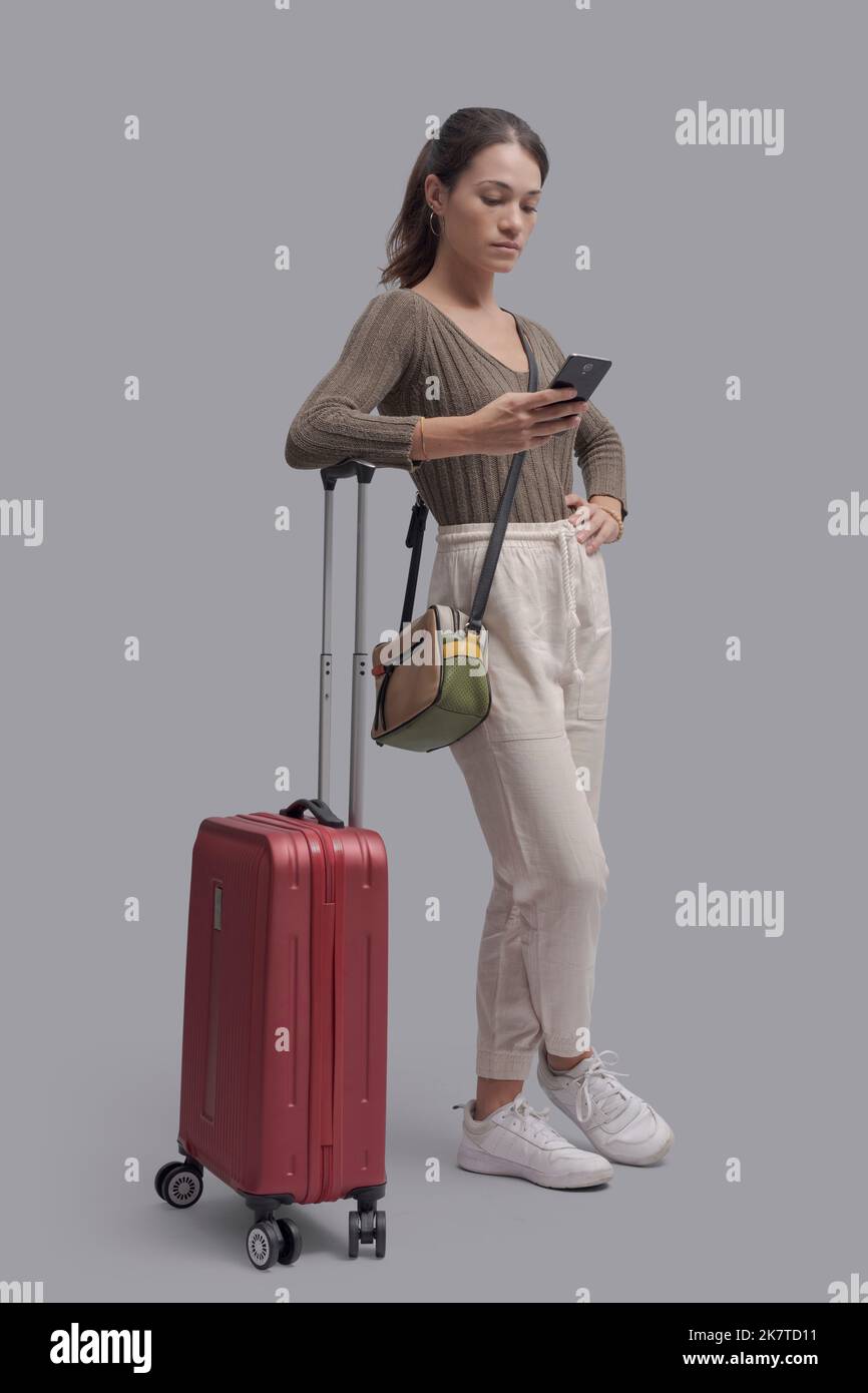 Young woman traveling alone and connecting with a smartphone, she is booking services online Stock Photo