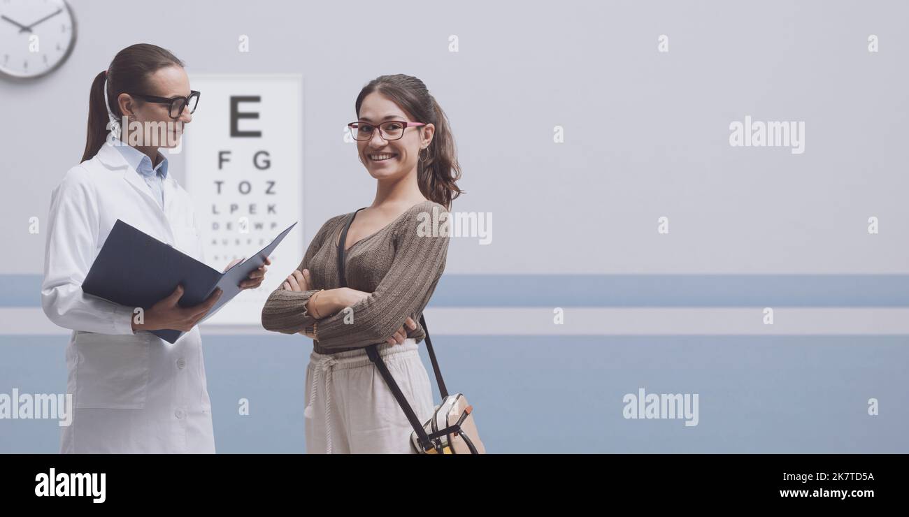 Young smiling woman wearing glasses and talking with her professional optometrist, she had an eye exam and vision test Stock Photo