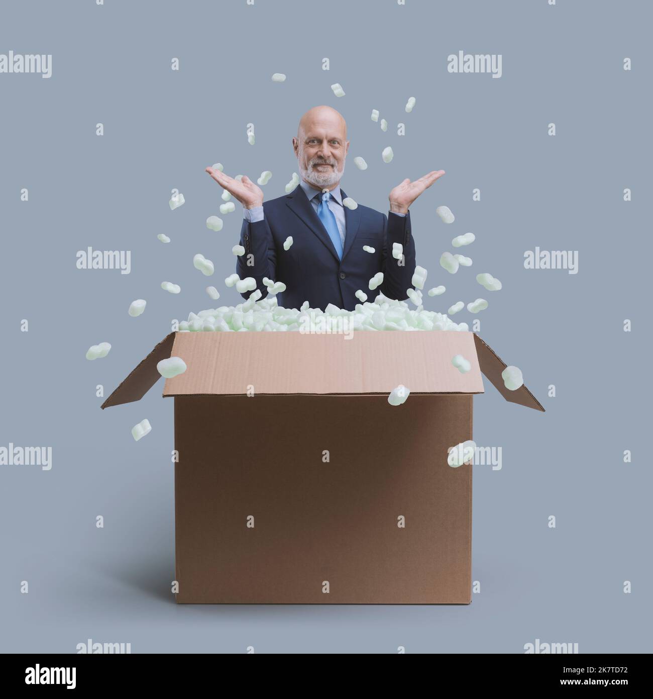 Smiling corporate businessman popping out from a delivery box, business ...