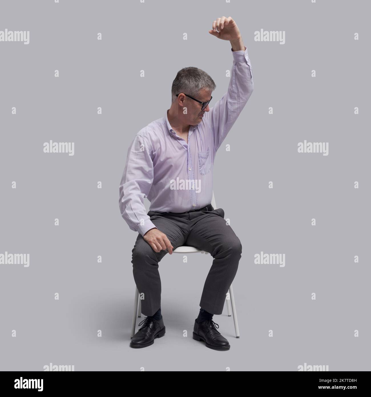 Emotional stressed man sitting on a chair and sweating, his shirt is