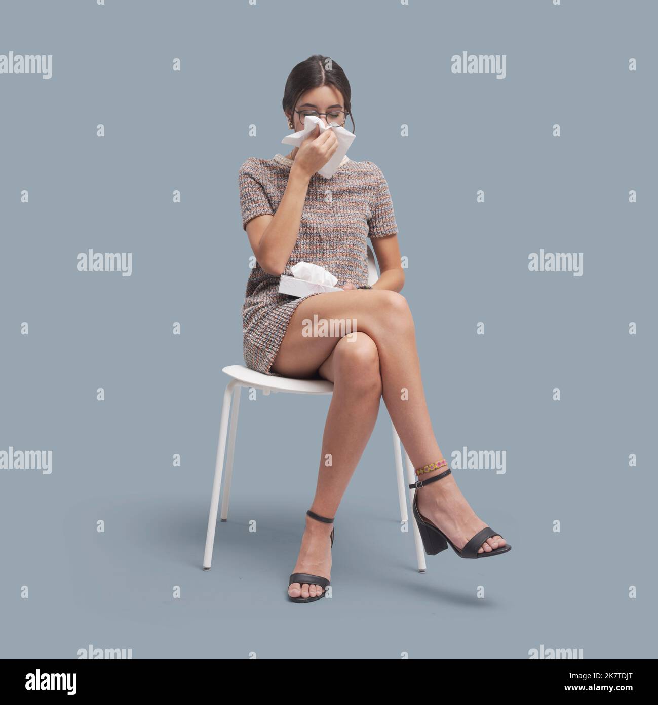 Patient sitting on a chair and waiting, she has cold and flu and she is blowing her nose, healthcare and medicine concept Stock Photo