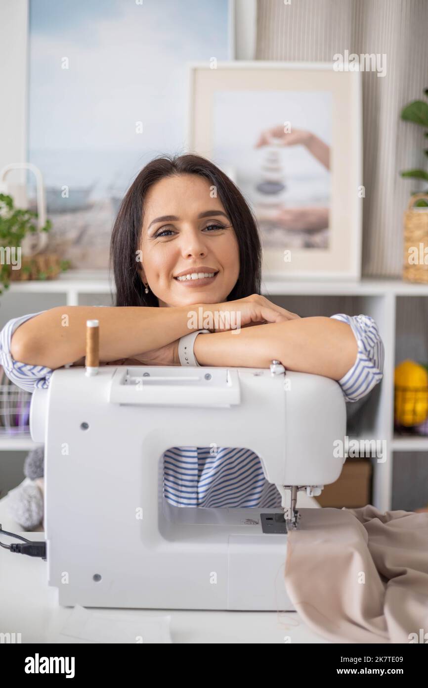 Portrait happy woman tailor dressmaker posing at workplace electric
