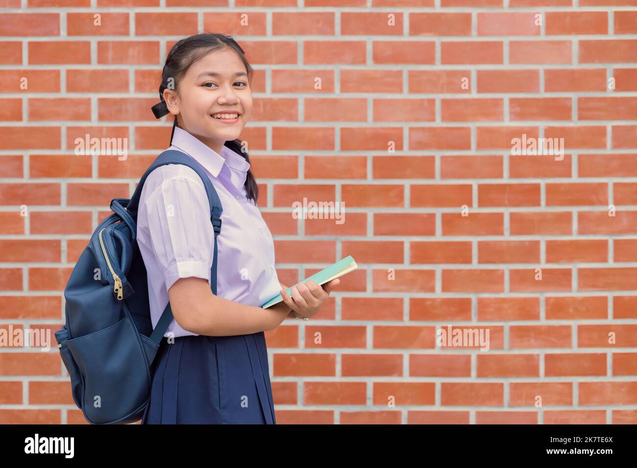 Thai asian school girl teen happy smile in uniform handle book and school bag with copy space Stock Photo