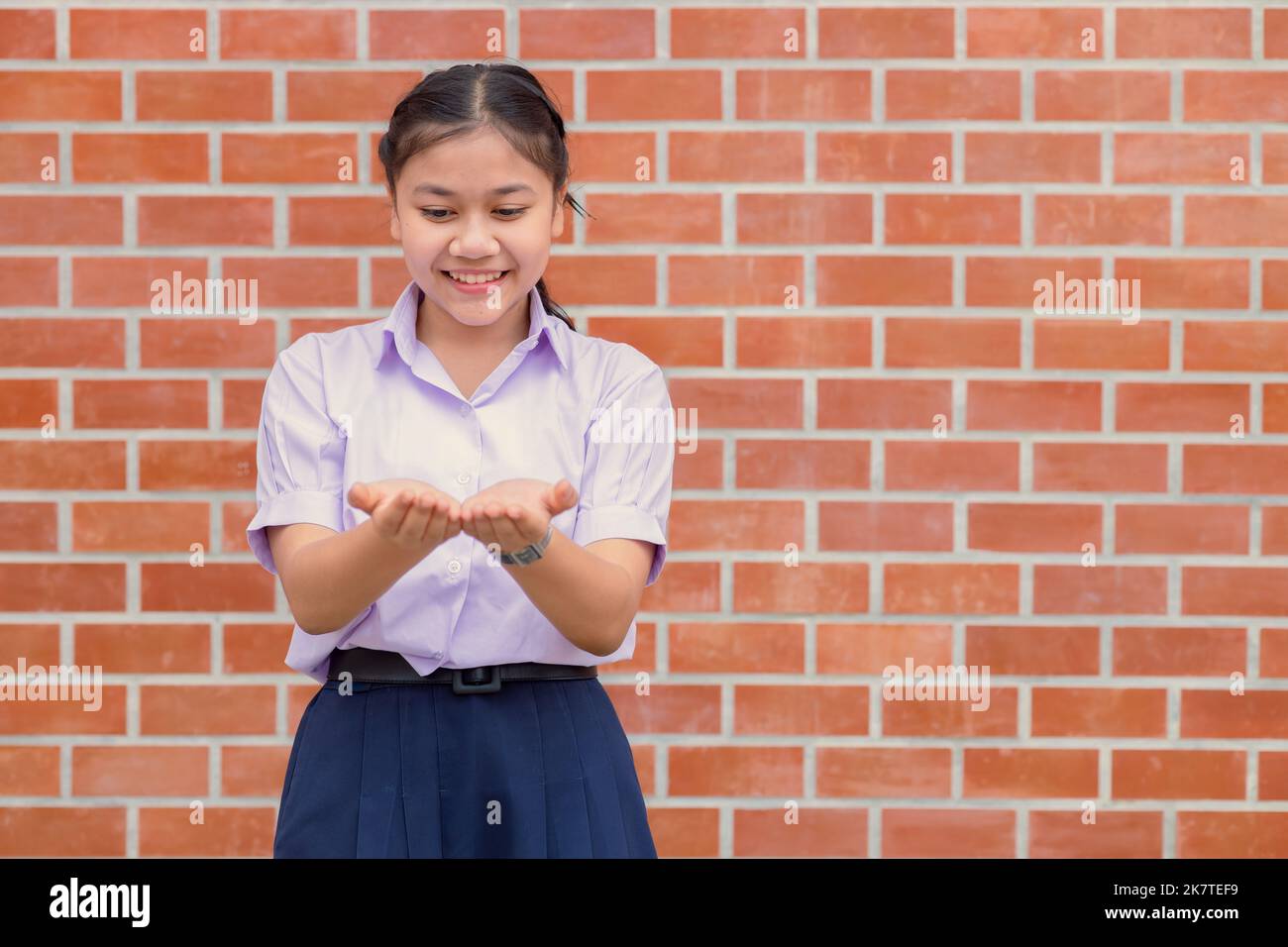 Asian school girl looking at two palm amazing thing in hand show present education concept Stock Photo