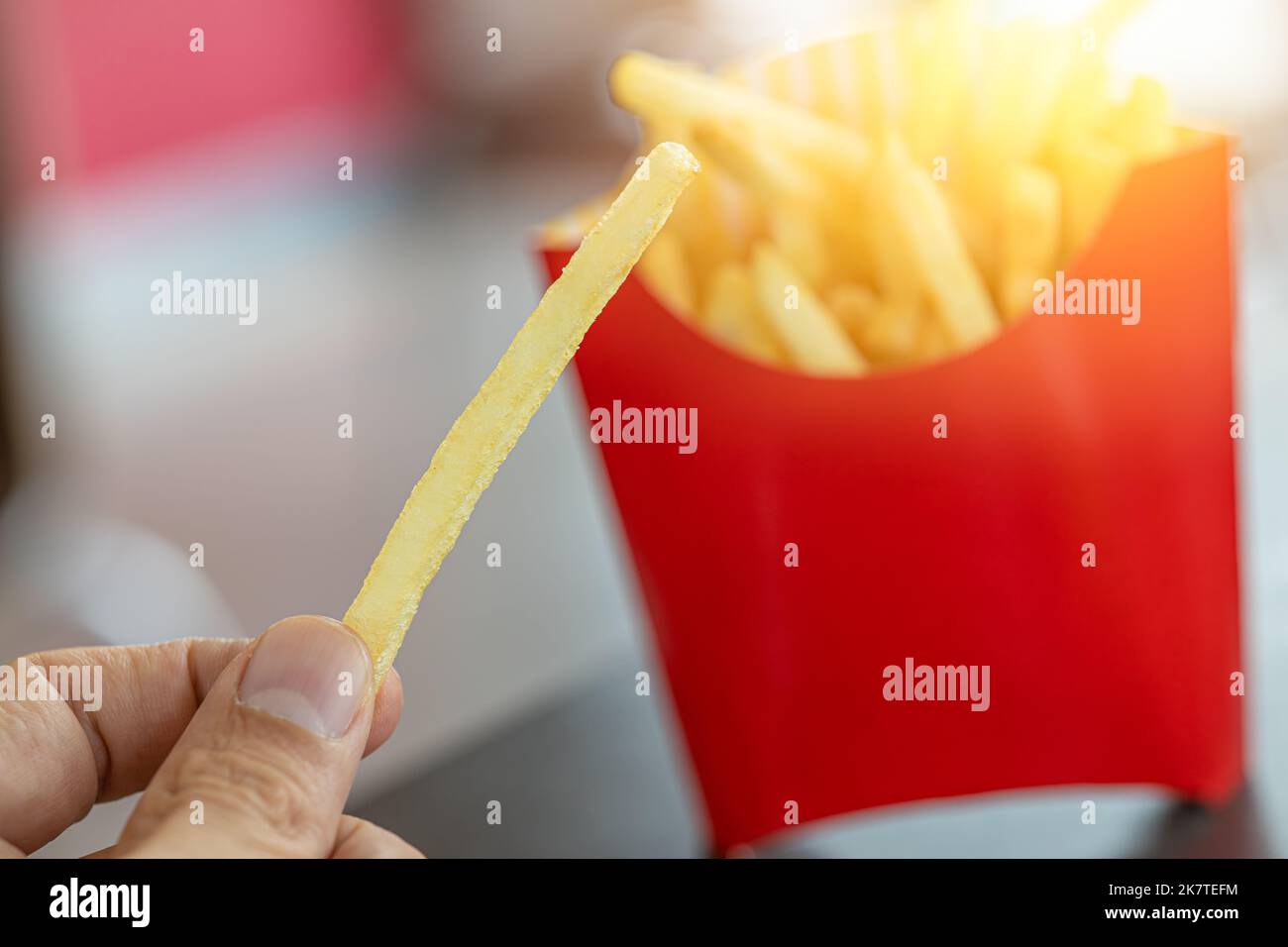 french fries. closeup male hand holding golden potato stick fry popular american fast food. Stock Photo