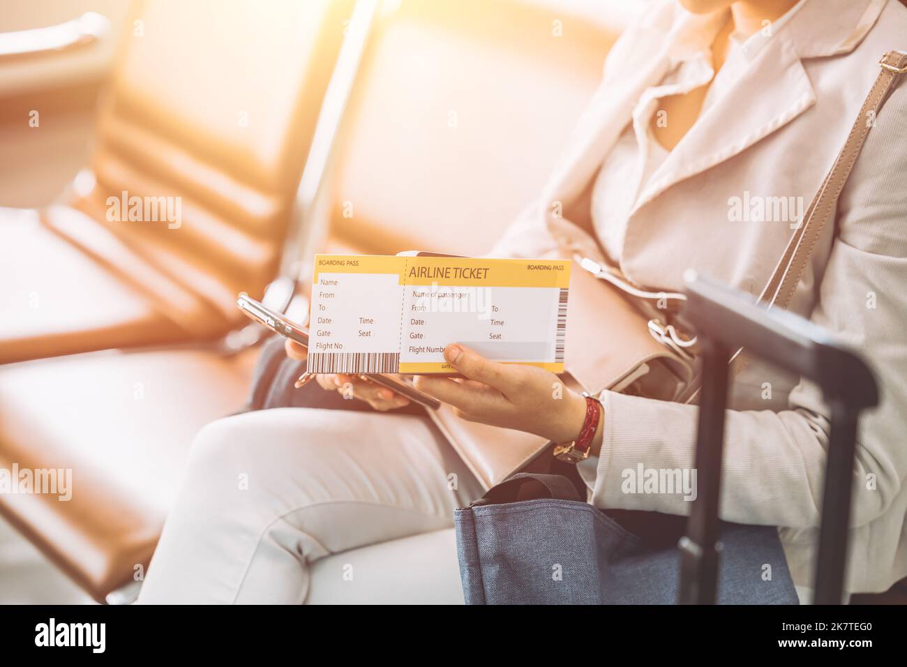 traveller sitting in waiting area with boarding pass ticket self check in using smartphone application Stock Photo