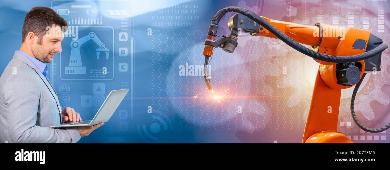 senior robotic programmer with laptop control robot welding arm for new generation industry technology banner concept Stock Photo