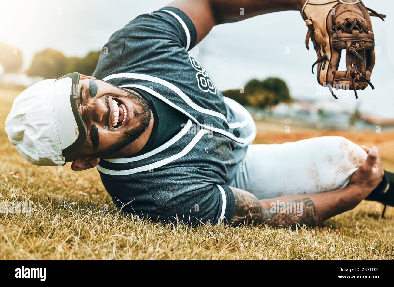 Baseball player, sports injury and knee pain with athlete man on grass pitch for leg osteoporosis and fibromyalgia. Health, injured and male with Stock Photo