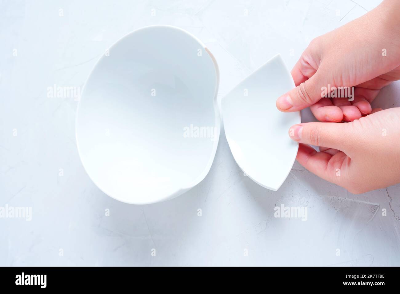 Broken bowl piece in hands, topview. Fixing cracked dishware Stock