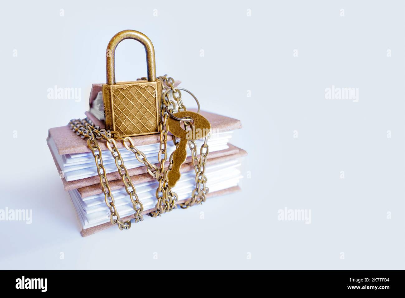 Miniature paper journals secured with chain and keyed padlock. Outsource bookkeeping security practices. Stock Photo