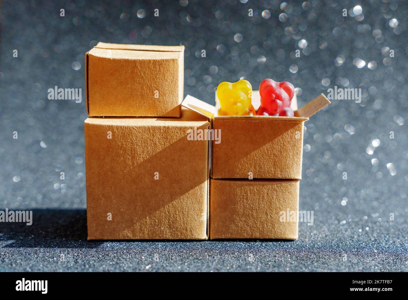 Two colorful gummy bears peeping out of a shipping box isolated on a