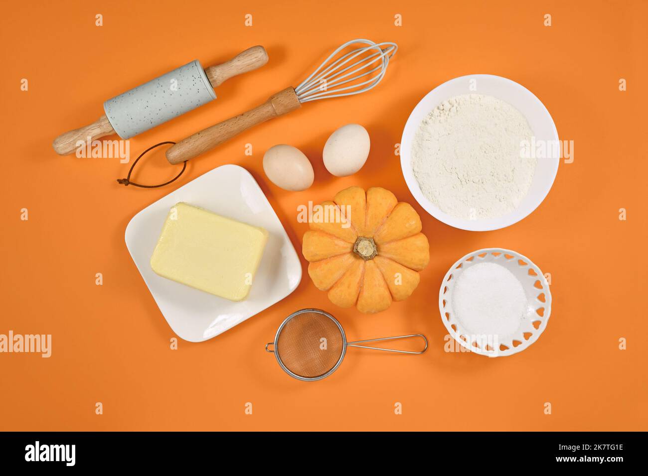 Pumpkin pie ingredients and baking tools on orange background Stock Photo