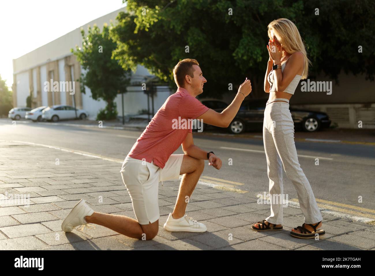 Young man with engagement ring making proposal to his beloved girlfriend outdoors.  Stock Photo