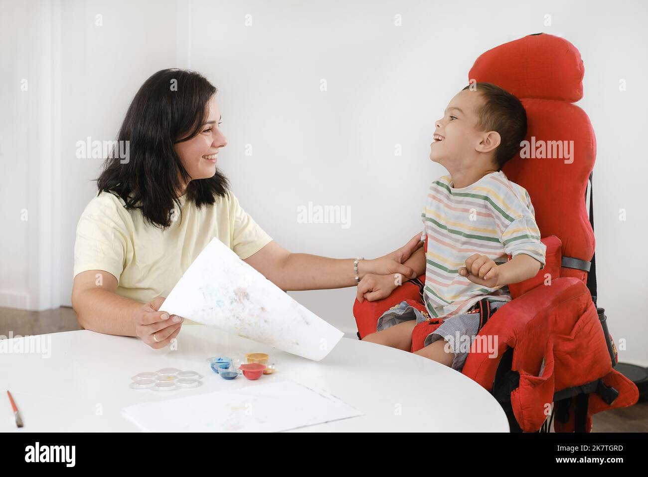 Child with cerebral palsy painting with fingers and hands boy that has