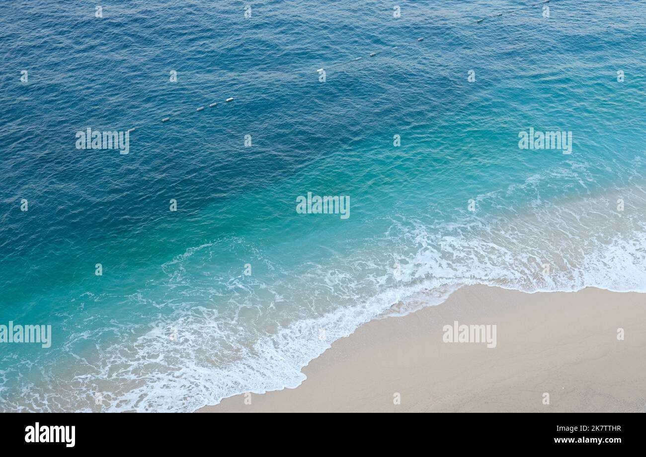 Turquoise sea holiday concept from above. Empty beach from above with sea and sand. Holiday background with turquoise sea and sand. Open space area. Stock Photo