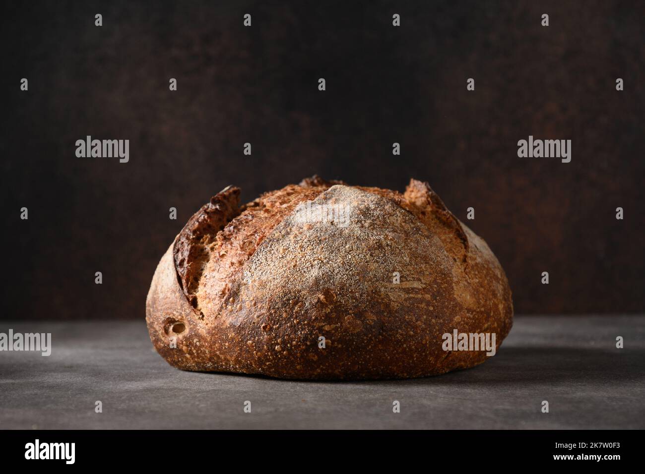 Loaf of freshly baked whole grain bread on brown background. Close up ...
