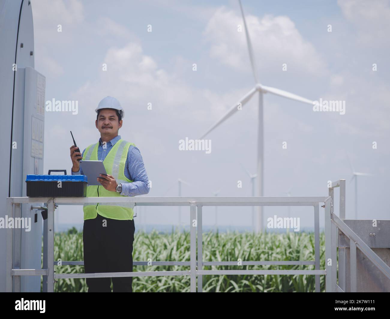 Engineer man is using a tablet to control and monitor the operation of a wind turbine in the